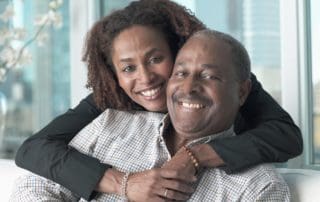 A daughter hugs her father, both smiling with satisfaction after dental treatment.