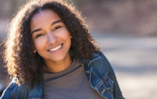 A teenage girl smiling brightly, showcasing her radiant smile.