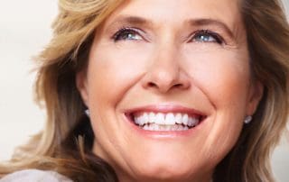 A mature female patient displaying a satisfied smile after receiving teeth whitening services from Pike District Smiles.