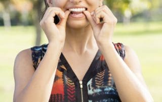 Teenager joyfully putting on Invisaligners at Pike District Smiles.