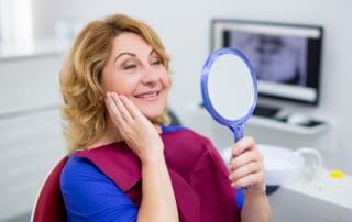 Patient smiling after seeing her teeth in the mirror.