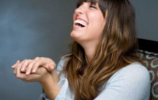 Joyful female patient sitting with wide open mouth, displaying her bright teeth.