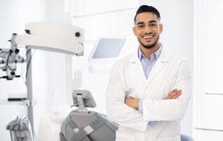 Dentist posing in front of the dental chair with a radiant smile.