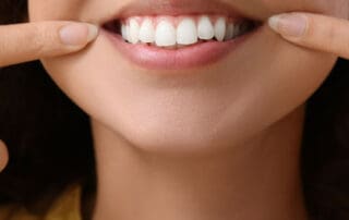 Satisfied customer displaying her teeth by placing index fingers on both sides of the jaw.