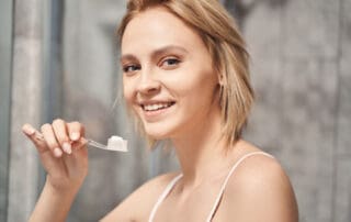 Female patient posing with toothbrush in hand, looking happy and satisfied.