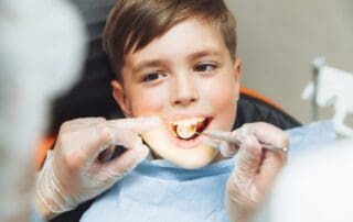 Happy child receiving dental treatment with wide open mouth and dental instrument inside.