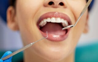Patient undergoing dental treatment with several dental instruments surrounding her mouth.