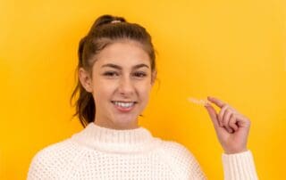Teen girl holding Invisalign aligners in her hand.