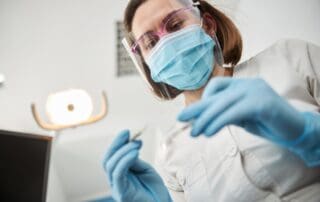 Dentist inspecting dental instrument.