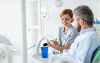 Dentist displaying dental treatment information on a tablet to the patient.